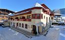 A charming building in winter with snow on the roof. Surrounded by snowy hills and blue sky.