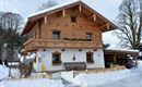 Ein schönes Holzhaus im Alpenstil, umgeben von schneebedeckter Landschaft. Es hat einen Balkon und eine gemütliche Atmosphäre.