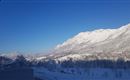 A snow-covered mountain landscape under a clear blue sky. The mountains are majestic and the scenery is calm and idyllic.