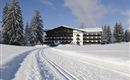 Ein charmantes Hotel umgeben von verschneiten Bäumen. Eine gut präparierte Loipe führt direkt zum Gebäude.