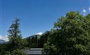 A clear blue sky over a picturesque landscape with green trees. In the foreground, there is a modern wooden building.
