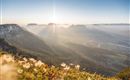 A stunning view of a mountain valley at sunrise. The gentle hills and the river in the valley are surrounded by fog.
