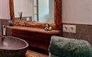 Een moderne badkamer met een houten wastafel en een rond wasbak. Op de tafel liggen zachte handdoeken en in de spiegel weerspiegelt zich een gezellige sfeer.