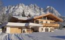 A beautiful, modern chalet in the snow, surrounded by majestic mountains. The calm winter landscape radiates coziness.