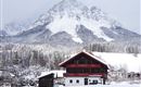 Eine malerische Berglandschaft mit schneebedeckten Gipfeln und einem traditionellen Chalet im Vordergrund. Der Winterzauber schafft eine ruhige und idyllische Atmosphäre.