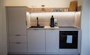 Een moderne keuken met minimalistische meubels en een elegante werkblad. Ze is uitgerust met een kraan, een koffiezetapparaat en een fornuis.