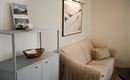 Een gezellige woonkamer met een beige bank en een kleine tafel. Aan de muur hangt een zwart-wit foto van een berglandschap.