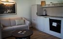Een moderne woonkamer met een comfortabele bank en een tafel. De keuken is licht en goed uitgerust.