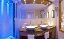 A modern bathroom with two sinks and an elegant shower. Bluish light creates a relaxed atmosphere.
