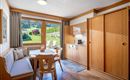 Eine gemütliche Ferienwohnung mit Holzinterieur und schöner Aussicht auf die grüne Landschaft. Der Raum bietet eine kleine Küche und einen Essbereich mit Tisch und Stühlen.