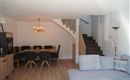 Ein modernes Wohnzimmer mit einem bequemen Couch und einem Essbereich. Eine Treppe führt in den oberen Bereich des Raumes.