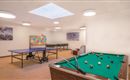 Een vrijetijdskamer met een biljarttafel en een tafeltennisbaan. De kamer heeft heldere verlichting en een ontspannen sfeer.