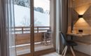 A modern room with a view of a snowy balcony. The room is bright and minimally designed.