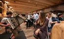 A sociable event in a restaurant with an accordion player.  
Guests enjoy drinks and chat in a warm, inviting atmosphere.