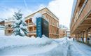 A picturesque hotel in the snow with modern wooden facades.  
The wintry landscape and deeply snow-covered surroundings create a cozy atmosphere.