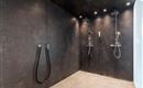 A modern shower with black wall paint and two showerheads. The floor is made of light tiles.