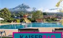 A beautiful pool with a view of the mountains and plenty of greenery. In the background, there are water slides and an inviting recreational area.