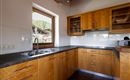 Eine moderne Küche mit Holzschränken und einer großen Fensteransicht. Die Arbeitsfläche ist aus schwarzem Material und bietet viel Platz zum Kochen.