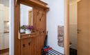 An inviting hallway with a wooden cabinet and a small mirror. Next to the cabinet are colorful umbrellas and a decorative storage holder.