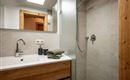 Een modern badkamer met een douche en een wastafel. De houten en tegel elementen geven de ruimte een hyggelige sfeer.