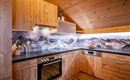 Een moderne keuken met houten kasten en een zwarte werkblad. Op de achtergrond is een indrukwekkend berglandschap afgebeeld.