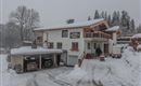 A beautiful house in the snow with a covered garage. The surroundings are wintry and peaceful.