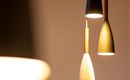 Hängende Lampen in modernen Formen leuchten sanft. Der Hintergrund ist neutral und betont die Beleuchtung.