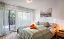 A cozy bedroom with a large bed and soft green colors.  
Large windows let in plenty of daylight and create a pleasant atmosphere.