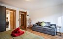 A modern room with a cozy sofa and a bed. The warm wood tones and the bright walls create an inviting atmosphere.
