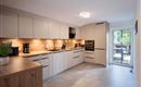 Modern kitchen with bright cabinets and wooden details. Large windows provide plenty of light and a view outside.