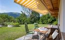 A cozy terrace area with two chairs and a table. In the background, you can see a green meadow and gentle hills.