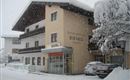 A cozy guesthouse in the snow with a large, snow-covered roof. The surroundings are wintry and picturesque.