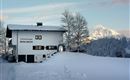 A picturesque holiday home in the snow named "Bergheim". In the background, snow-covered mountains and a clear sky can be seen.