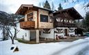A beautiful chalet in winter, surrounded by snow. The architecture combines traditional and modern elements.