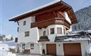 A modern house in Alpine style, surrounded by snow. The balcony and the wooden cladding give it a charming character.