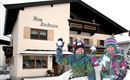 Zwei fröhliche Kinder spielen im Schnee vor einem gemütlichen Haus. Das Haus trägt die Aufschrift "Haus Landmann" und ist von Schnee umgeben.