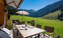 Ein schöner Außenbereich mit einem großen Esstisch und Sonnenschirm. Im Hintergrund sind grüne Berge und eine sonnige Landschaft zu sehen.
Chalet Heualm Kelchsau Kitzbüheler Alpen