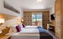 Doppelzimmer im Hotel Alpenpanorama in der Ferienregion Wilder Kaiser mit Holzmöbeln, gemütlicher Sitzecke und Ausblick ins Grüne.