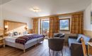 Großzügiges Doppelzimmer im Hotel Alpenpanorama in der Ferienregion Wilder Kaiser mit Sitzecke, Sofa, Schreibtisch und viel Tageslicht.