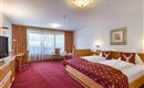 Komfortzimmer im Hotel Alpenpanorama in der Ferienregion Wilder Kaiser mit Boxspringbett, rotem Teppich und Balkonzugang.