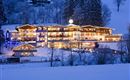 Ein gemütliches Hotel, das nachts im Schnee leuchtet. Umgeben von verschneiten Bäumen und einer winterlichen Landschaft.