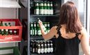 Eine Person steht vor einem Kühlschrank mit verschiedenen Bierflaschen. Im Hintergrund sind leere Kisten zu sehen.