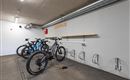 Ein moderner Fahrradabstellraum mit mehreren E-Bikes und Ladeanschlüssen. Die Wände sind schlicht und abweisend, was einen sauberen Eindruck hinterlässt.
