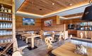 Een gezellig restaurant met houten wanden en moderne meubels. Tafels zijn netjes gedekt en een bar is op de achtergrond zichtbaar.