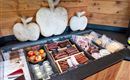Een selectie van vleeswaren en snacks ligt op een houten plank. Op de achtergrond zijn decoratieve houten appels te zien.