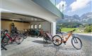 A garage with several bicycles and a beautiful mountain view. The surroundings are sunny and inviting.