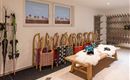 A cozy room with ski equipment and colorful bags. A wooden bench with a fur and a ski goggle are clearly visible.