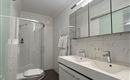 A modern bathroom with a shower and a sink. It has bright walls and an elegant, minimalist style.