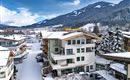 Ein Winterblick auf das Hotel mit schneebedeckten Dächern und umliegenden Bergen. Die Landschaft ist friedlich und einladend.