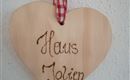 A heart-shaped wooden plaque with the inscription "Haus Jolien". It is equipped with a red checked ribbon for hanging.